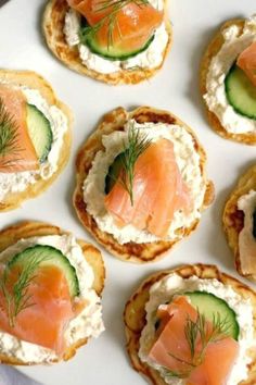 small appetizers with smoked salmon and cucumber on them are arranged on a white plate