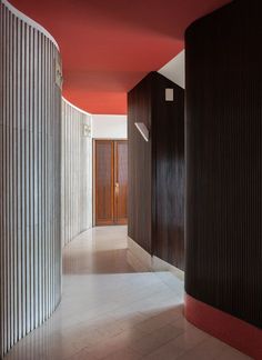 the hallway is lined with black and white vertical striped walls, along with an orange accent wall