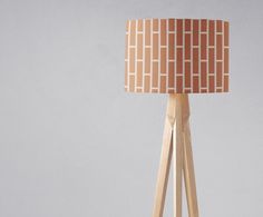 a wooden tripod floor lamp with a brown and white fabric shade on the top