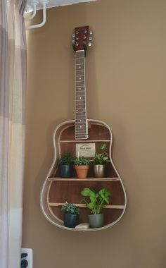 a guitar shaped shelf with potted plants on it