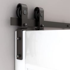 two black rollers are attached to the side of a white door with metal handles