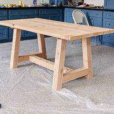 a wooden table sitting on top of a kitchen floor next to a blue countertop