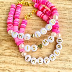 pink and white bracelets with the word she wrote on them, sitting on a wooden surface