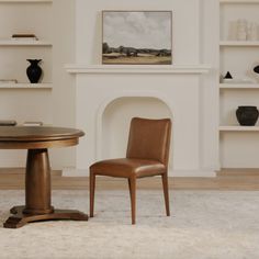 a chair and table in front of a fireplace with shelves on the wall behind it