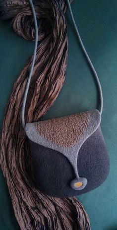 a bag made out of yarn and wood on top of a green surface with a cord hanging from it