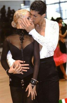 two women in black and white outfits kissing each other