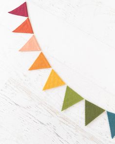 multicolored felt pennant on white wood background