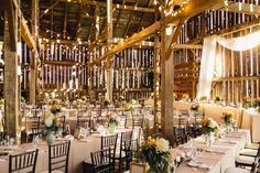 the inside of a barn with tables and chairs set up for an elegant wedding reception