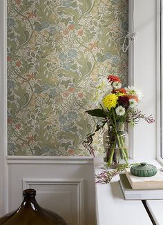 a vase filled with flowers sitting on top of a white table next to a window