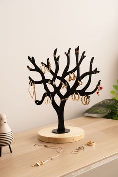 a black tree with earrings on it sitting on top of a table next to a clock