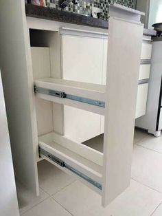 an open cabinet door in a kitchen next to a counter top with drawers on it