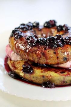 two pancakes covered in blueberry sauce on top of a white plate next to each other