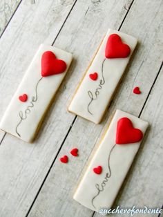 three decorated cookies with red hearts on them