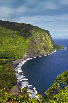 an ocean view from the top of a hill with trees and bushes on either side