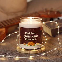 a candle that is sitting on a table next to some string lights and a guitar