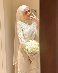 a woman in a wedding dress taking a selfie with her cell phone while holding a bouquet of flowers