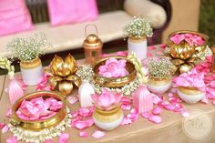 a table topped with lots of vases filled with flowers next to candles and plates