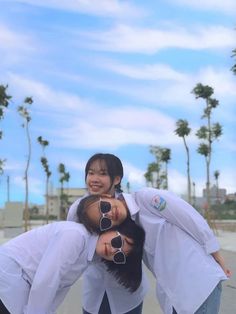 three young women are posing for the camera with their arms around each other in front of palm trees