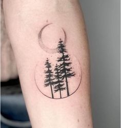 a black and white photo of trees with a half moon tattoo on the left arm