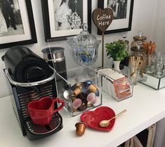 a coffee bar with cups, mugs and other items on the counter in front of pictures