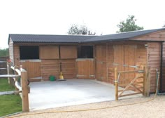 a horse stable with wooden doors and windows