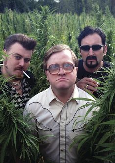 three men are standing in the middle of a field with marijuanas on their heads