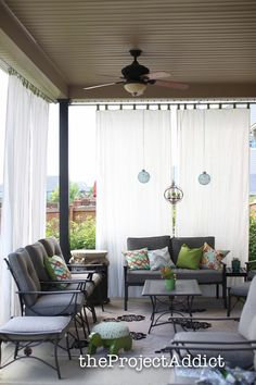 a covered patio with chairs and tables under a ceiling fan