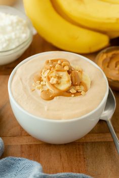 a bowl of oatmeal with bananas and peanut butter in the background on a wooden table