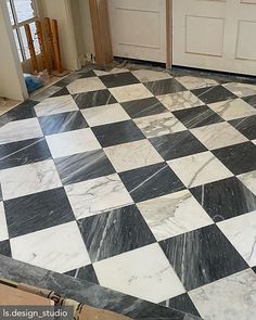 a black and white checkered tile floor in a house under construction with the door open