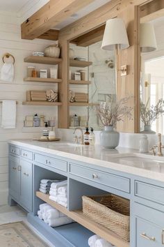 a bathroom with blue cabinets and shelves filled with white towels, soaps and other items