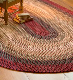 a chair and rug on the floor in front of a wooden table with a stack of books