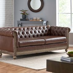 a brown leather couch sitting on top of a wooden floor next to a white rug