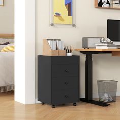 a desk with a computer on top of it next to a bed in a room