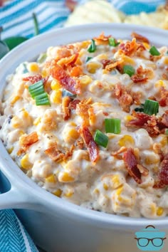 a close up of a bowl of food with corn and bacon in it on a table