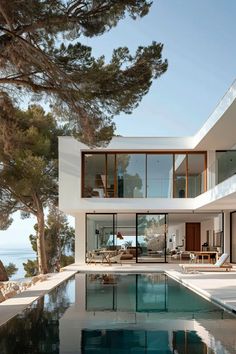 a house with a pool in front of it and some trees around the pool area