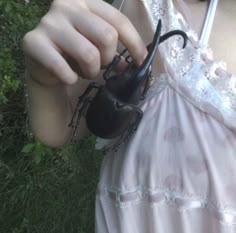 a woman in pink dress holding up a black spider