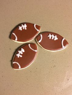 three chocolate football shaped cookies sitting on top of a table