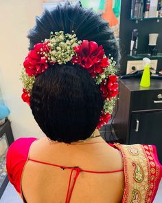 the back of a woman's head with red flowers in her hair and an elaborate braid