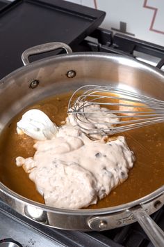 a pan filled with food and whisk on top of a stove