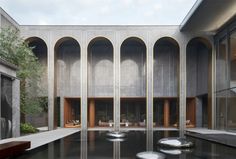 an empty courtyard with benches and tables in the foreground, surrounded by concrete arches