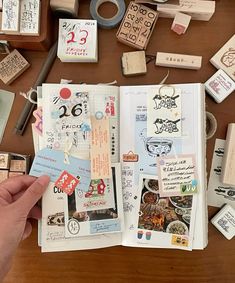 an open book with lots of stamps and magnets on the table next to it