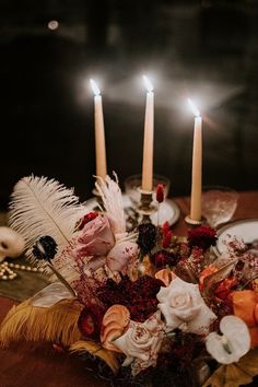 a table topped with candles and flowers on top of a wooden table