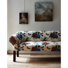 a couch sitting on top of a wooden floor next to two pictures hanging on the wall