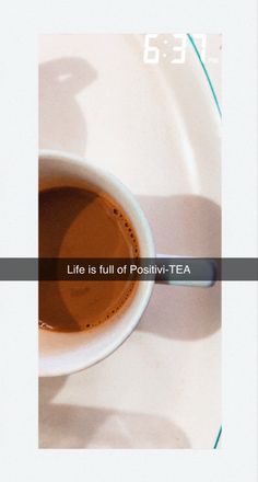 a cup of tea sitting on top of a white plate next to a spoon with the words life is full of positiv - tea