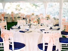 the tables are set with blue and white linens for an elegant wedding reception in a tent