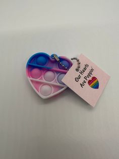 two heart shaped trays with tags attached to them on a white surface, one is pink and the other is blue