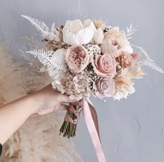 a person holding a bridal bouquet with pink and white flowers on it's side