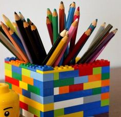 a lego desk organizer with colored pencils in it and a cup full of crayons