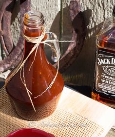 a bottle of jack daniels whiskey sitting on top of a wooden table next to another bottle