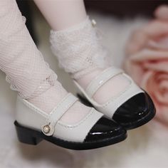 a doll's feet wearing white socks and high heeled shoes with lace on them